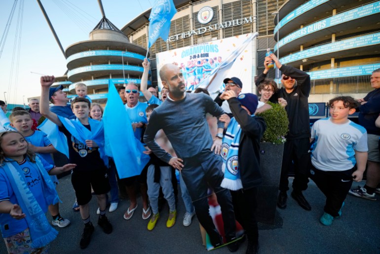 Manchester City supporters hold a cutout of Manchester City's head coach Pep Guardiola 