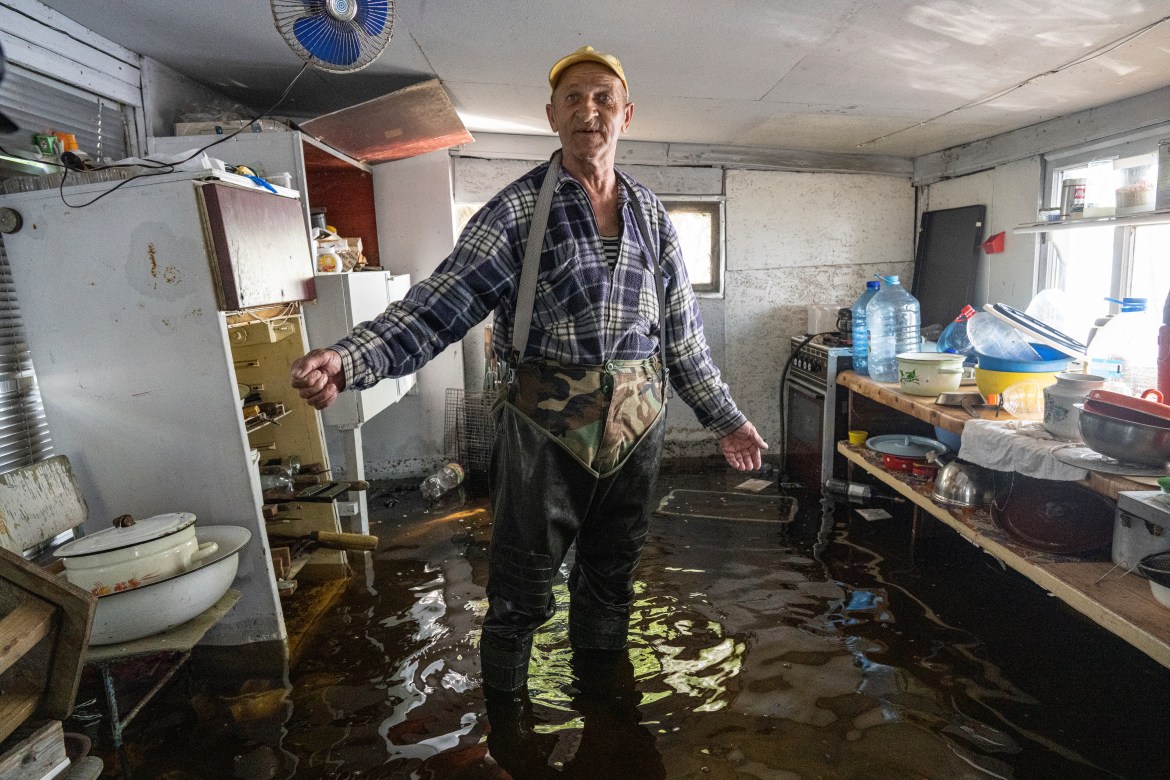 Mykola Gurzhiy, 74, a local fisherman stands at the kitchen of his flooded house