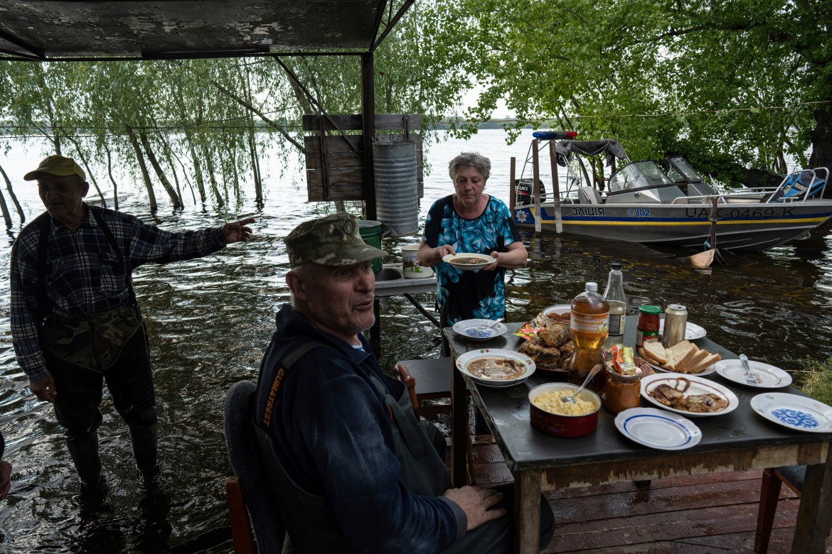 Lyudmila Kulachok, 54, right, sets the food on the table for family diner at the flooded courtyard