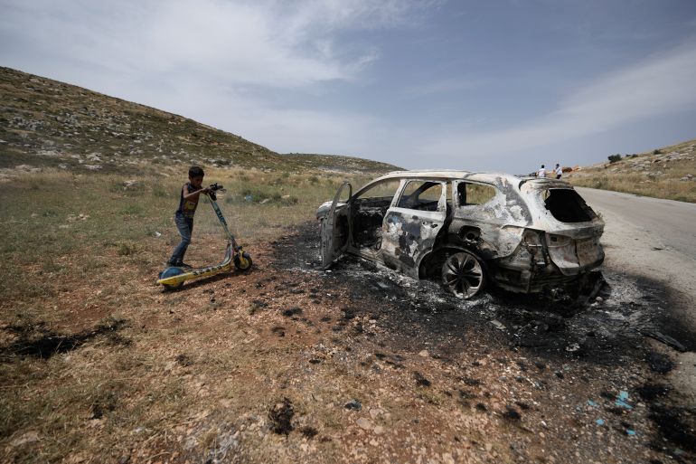 A Palestinian child inspects a burnt car, which farmers say was set on fire by Israeli settlers, in the village of al-Mughayyir near the West Bank city of Ramallah, Friday, May 26, 2023. Jewish settlers attacked Palestinian farmers and torched five vehicles in the village, the official Palestinian news agency reported. It added that five farmers were injured when settlers beat them. There was no immediate comment from the Israeli military.(AP Photo/Majdi Mohammed)