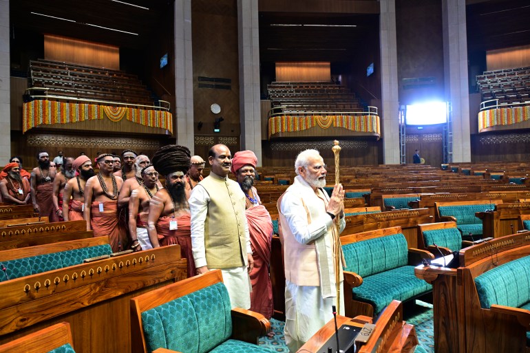O primeiro-ministro indiano Narendra Modi carrega um cetro real de ouro para ser instalado próximo à cadeira do orador durante o início da cerimônia de inauguração do novo prédio do parlamento, em Nova Delhi, Índia, domingo, 28 de maio