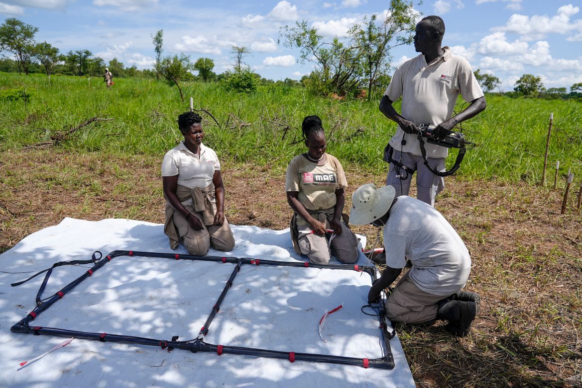 Deminers from the Mines Advisory Group (MAG) prepare to do clearance at a site containing cluster munitions in Ayii
