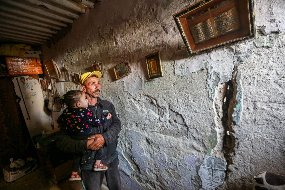 Basil Al-Aqra_, Rola_s husband, next to a wall affected by the bombing last night, next to their house in Deir Al-Balah, central Gaza Strip-1683179224