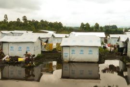 Tents perched on the edge of a rain puddle in Bushagara camp, DRC [Sophie Neiman/Al Jazeera]