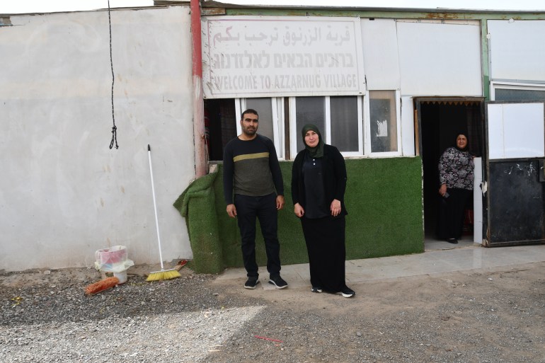 Mohamed Abu Qwaider, his wife and mother-in-law stand in front of their house in the unrecognized village of Az-Zarnug
