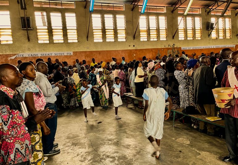 Displaced families and residents of Goma dance at a Sunday morning church service. [Sophie Neiman/Al Jazeera.]