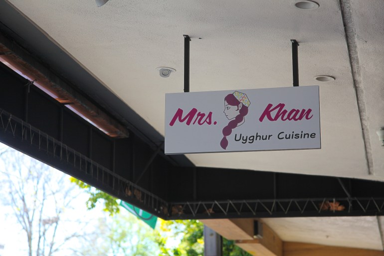 A sign for Mrs Khan Uyghur Cuisine hangs from an awning.