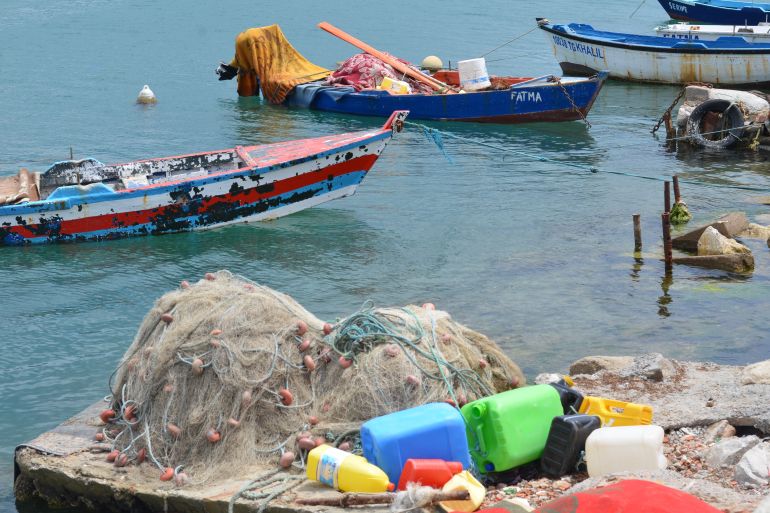 rowboats in the sea with colorful plastic bottles on the rocks