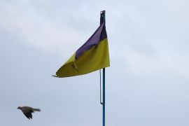 A pigeon flies past a Ukrainian flag on top of the cultural house during heavy fighting at the front line of Bakhmut and Chasiv Yar, in Chasiv Yar, Ukraine, April 11, 2023.