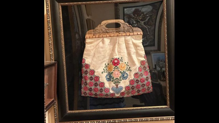 An embroidered sack framed on the wall of Leila's home
