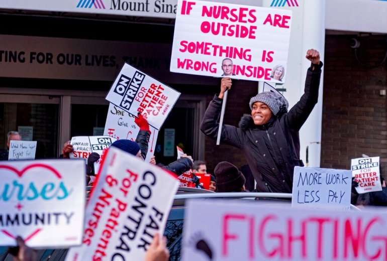 Nurses hold signs as they protest on a picket line