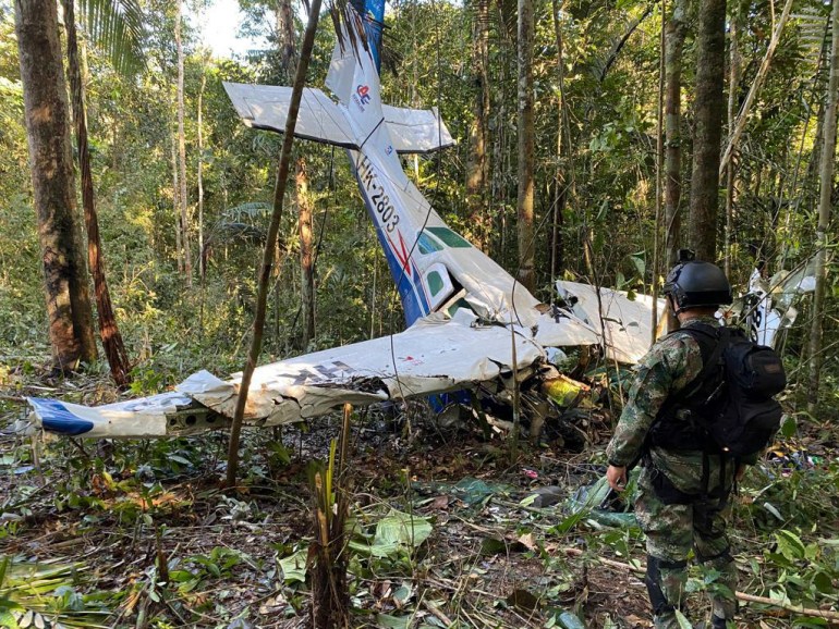 A soldier stands near the wreckage of a plane in the forest