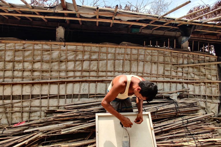 El esposo de Nur Ayesha arreglando el panel solar frente a su refugio dañado