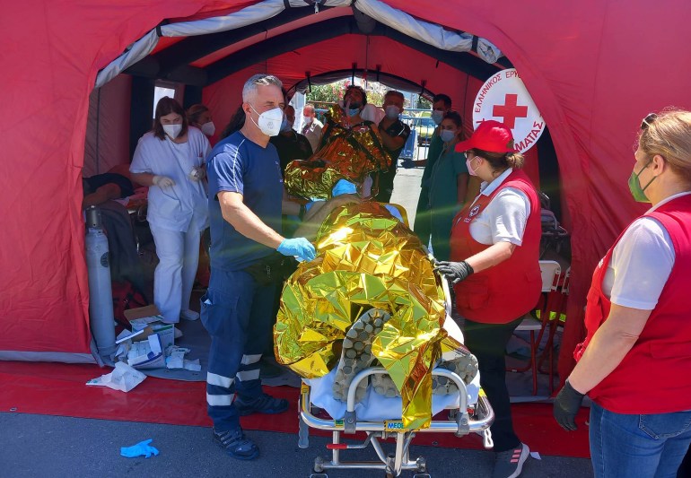 Des ambulanciers paramédicaux du Service national d'ambulance d'urgence grec (EKAV) et des membres de la Croix-Rouge grecque assistent les migrants vers le port de Kalamada.
