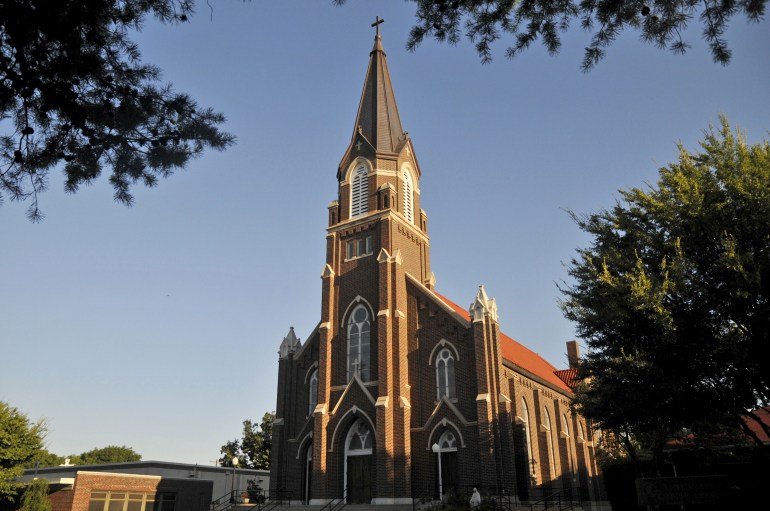 A brick Catholic church with a steeple, seen from the outdoors in Guthrie, Oklahoma.