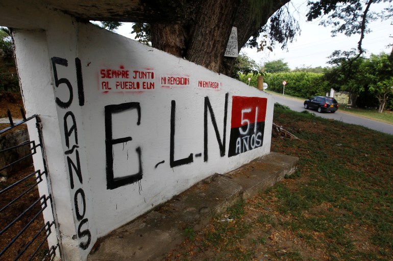 A white wall outside a cemetery has the letters "ELN" and "51 años" painted on it.