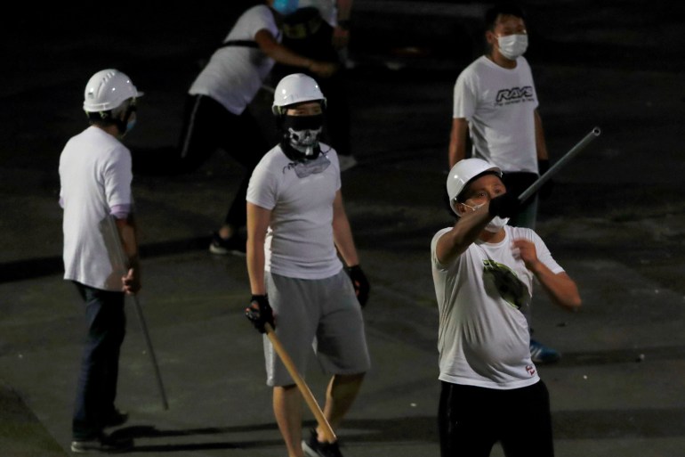 Armed men in white T-shirts and helmets at the Yuen Long Station in July 2019