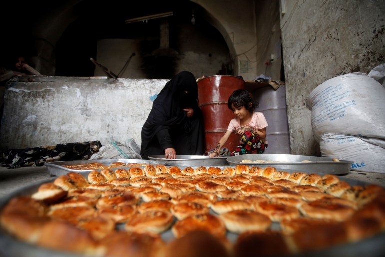 A woman and a girl prepare cookies for the Eid al-Adha festival at the old quarter of Sanaa, Yemen