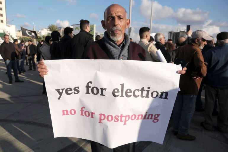 A man holds a banner during a protest against the delay to the Libyan presidential election