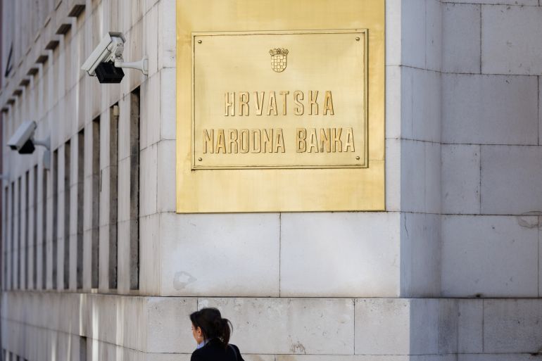 A woman passes a sign on the building of Croatian National Bank in downtown of Zagreb, Croatia, February 7, 2022.