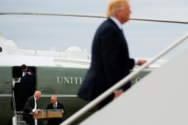 Trump boardng a plane when president. There are officials behind with boxes of documents.