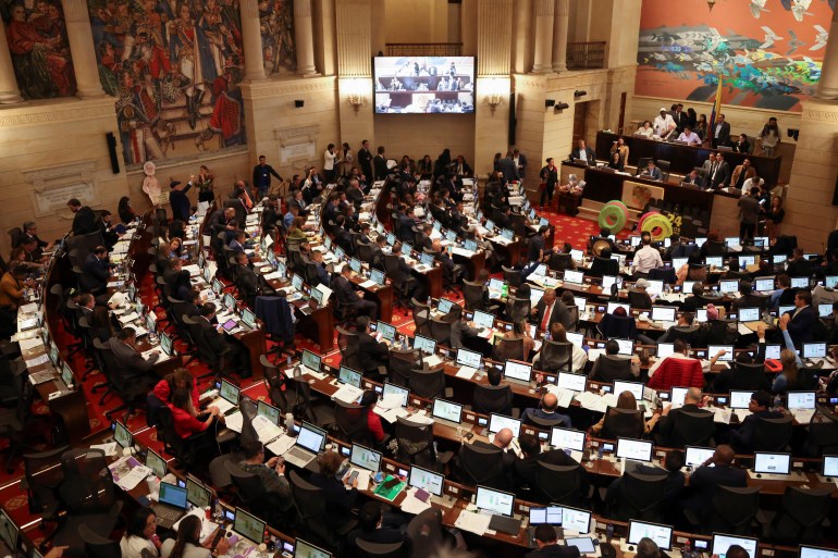 Une vue aérienne du Congrès colombien, assis à des tables en rangées d'arcs concentriques dans le bâtiment du congrès.