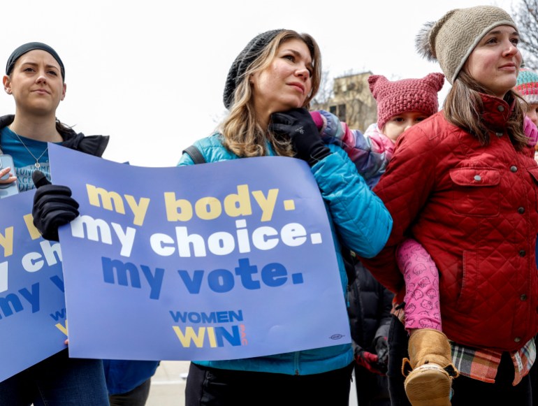 A woman holds a sign that says: "My body.  My choice.  My vote."