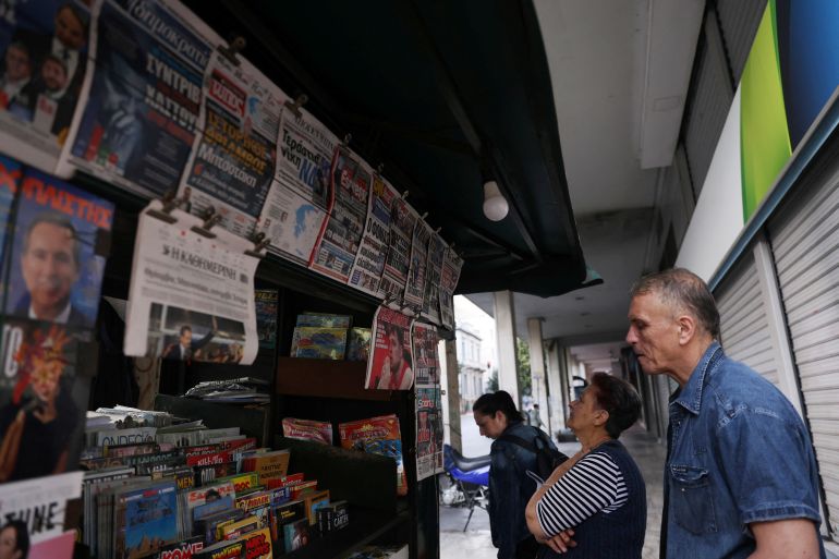 People read newspaper headlines at a kiosk in Athens