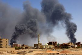 A man walks as smoke rises above buildings after an aerial bombardment in Khartoum North, Sudan [File: Mohamed Nureldin Abdallah/Reuters]