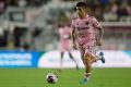 Inter Miami player in pink readying to kick soccer ball