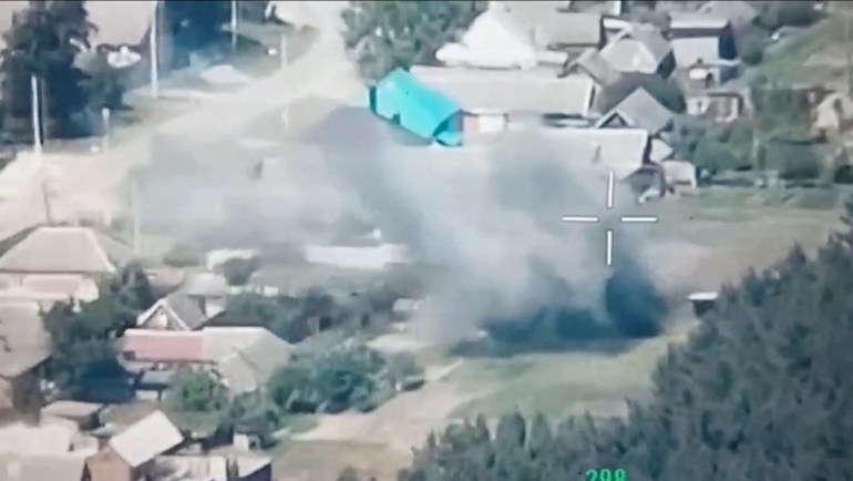 Un fermo immagine tratto da filmati di droni rilasciati dal Freedom Corps of Russia mostra un attacco a Belgorod.  Costruire tetti visibili, esplosioni e molta polvere e terra.