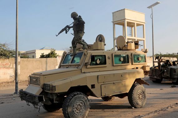 A soldier serving in the African Union Mission in Somalia jumps off a military vehicle in Mogadishu, Somalia