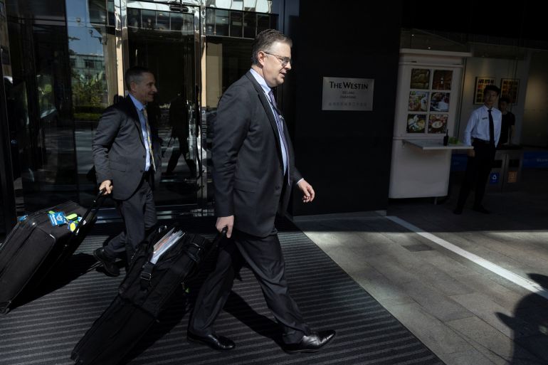 US Assistant Secretary of State for East Asian and Pacific Affairs Daniel Kritenbrink leaving a Beijing hotel. He is in a suit and pulling a suitcase.