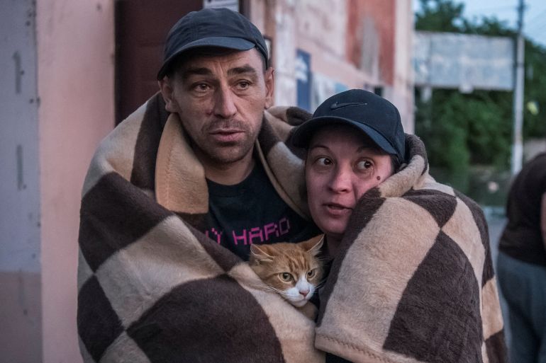 A man and a woman wrapped in a brown blanket as they evacuate following the breach of the Nova Kakhovka dam