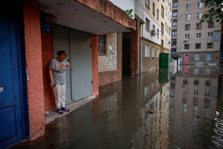 Olena stands next to the entrance to her house on a flooded street, after the Nova Kakhovka dam breached, amid Russia's attack on Ukraine, in Kherson, Ukraine June 6, 2023. REUTERS/Alina Smutko