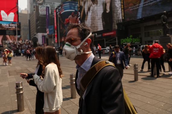 A man wears a face mask through Times Square in New York City due to poor air quality linked to wildfires in Canada