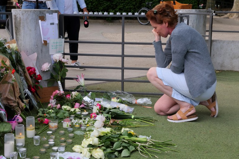 A woman pays respect in front of messages and floral tributes at the children's playground the day after several children and adults were injured in a knife attack at the Le Paquier park near the lake in Annecy, in the French Alps, France