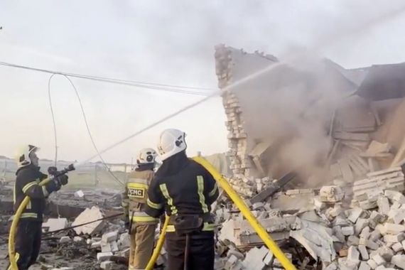 Firefighters work at a site of a damaged building