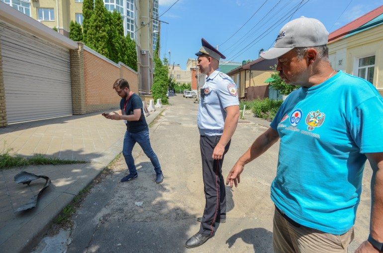 A police officer stands guard as a journalist films near a damaged multi-storey apartment block following a reported drone attack in Voronezh, Russia June 9, 2023. REUTERS/Vladimir Lavrov