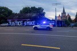 A police car drives past a graffiti calling for justice for Mike Ben Peter in Lausanne, Switzerland