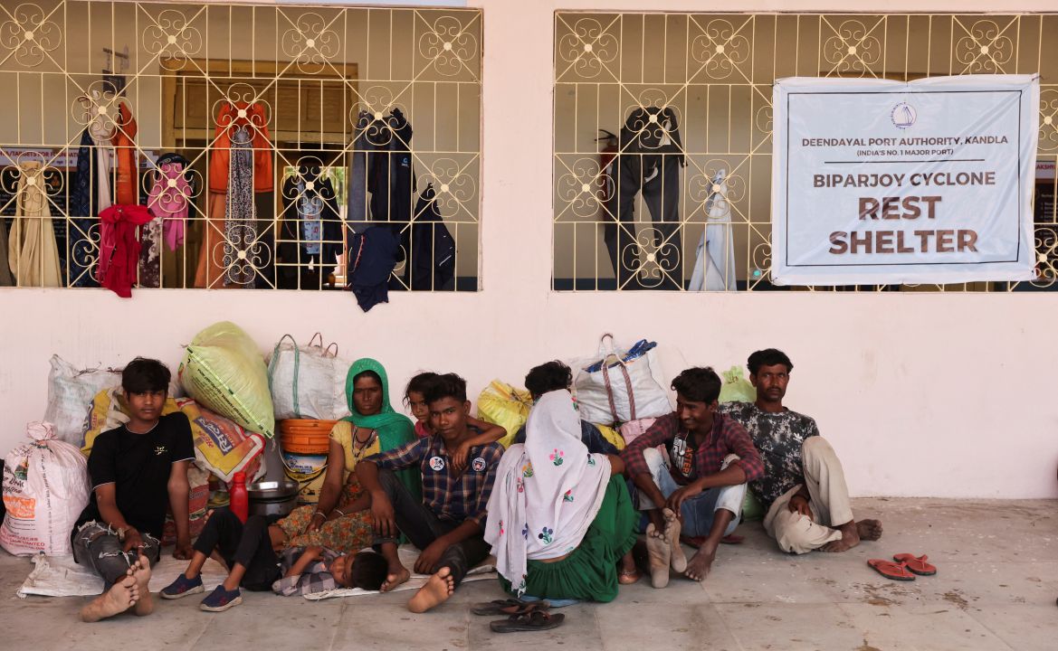 People evacuated from Kandla port sit outside a school converted into a shelter