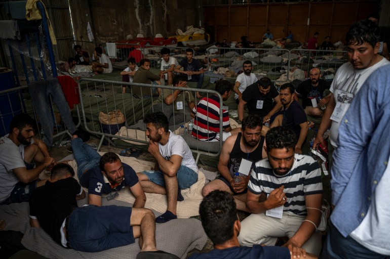Migrants who were rescued at open sea off Greece along with other migrants, after their boat capsized, are seen inside a warehouse, used as shelter, at the port of Kalamata, Greece, June 15, 2023. Angelos Tzortzinis/Pool via REUTERS