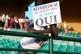 A man hold a sign as he attends the last campaign rally om Bamako