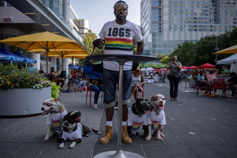 Casius Caligula watches a band with his pit bull dogs Mephistopheles, Maximilian, Medusa and Maleficent during Juneteenth festivities at Discovery Green in Houston, Texas