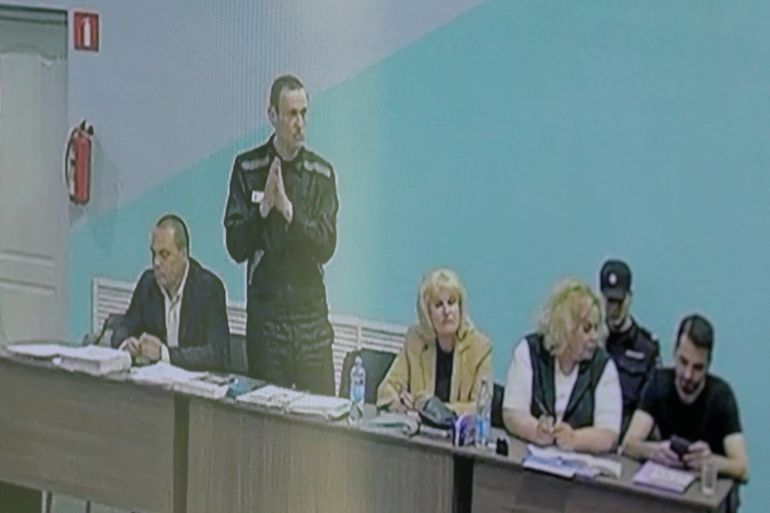 Russian opposition politician Alexei Navalny, his lawyers Olga Mikhailova and Vadim Kobzev and other participants are seen on a screen via a video link during an external hearing of the Moscow City Court in a new criminal case against Navalny on numerous charges, including the creation of an extremist organization, at the IK-6 penal colony in the Vladimir region, Russia, June 19, 2023. REUTERS/Evgenia Novozhenina