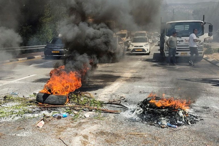 Burning tires block a road after Druze residents protest against plans to build a series of wind turbines