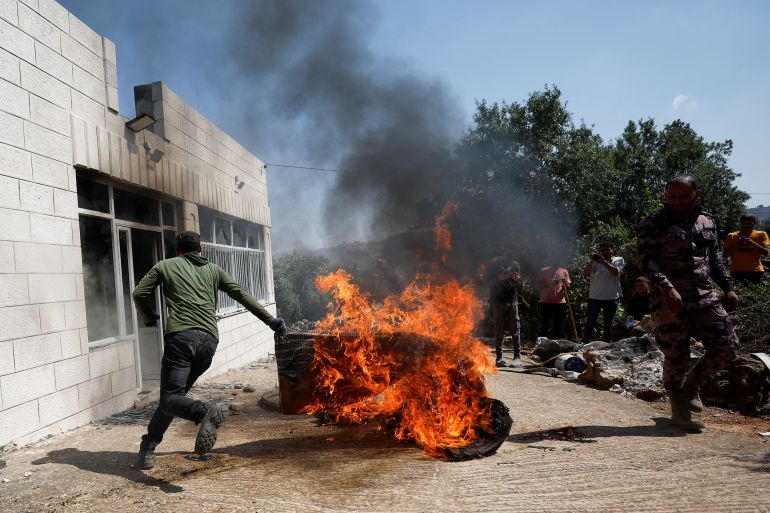 A Palestinian man runs near a burning object, after an attack by Israeli settlers, near Ramallah, in the Israeli-occupied West Bank, June 21, 2023