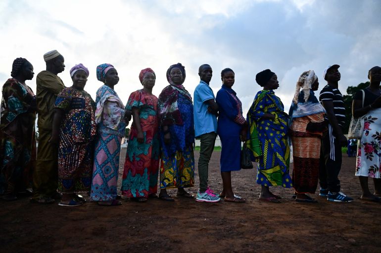 People wait to cast their votes for the national election at a polling station in Freetown
