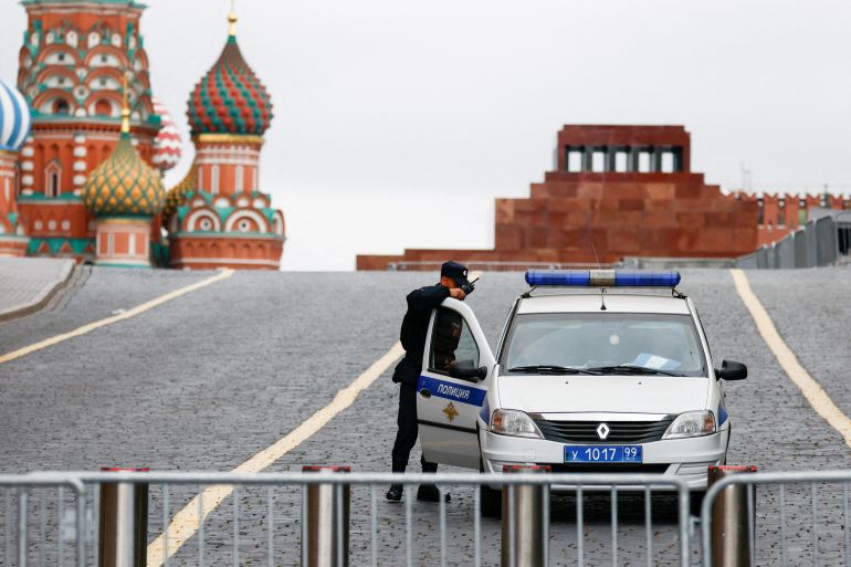 A view of Red Square and St Basil's Cathedral. The square is fenced off and there is a police car behind the barrier. An officer is by the car door.
