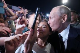 Russian President Vladimir Putin kisses a participant of a meeting in a street in Derbent in the southern region of Dagestan